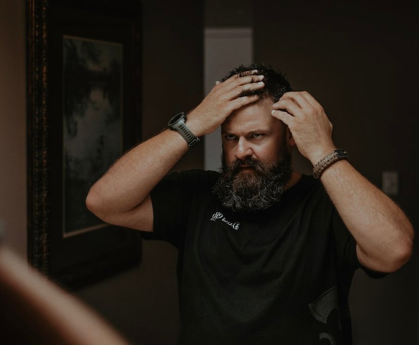 Man examining thinning hair in the mirror